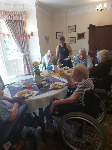 Residents dining together in the bright conservatory lounge