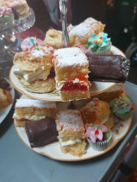 Tiered cake stand with scones, cream, and handcrafted pastries